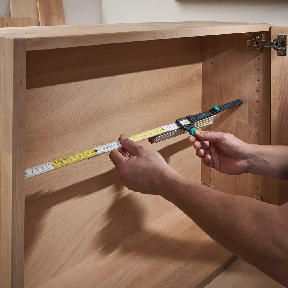 Adaptador colocado en un metro carpintero, facilitando la medición del ancho interior de un mueble
