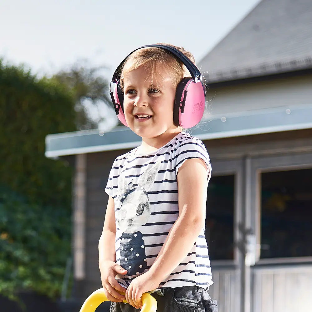 La hija de un carpintero usando sus audífonos wolfcraft rosa para reducir el ruido que generan las herramientas del taller
